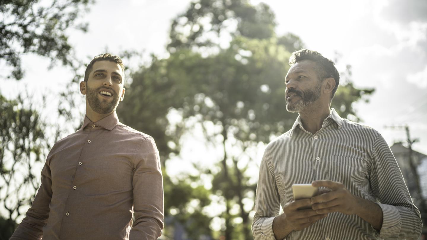 Men in business attire walking outside holding coffee