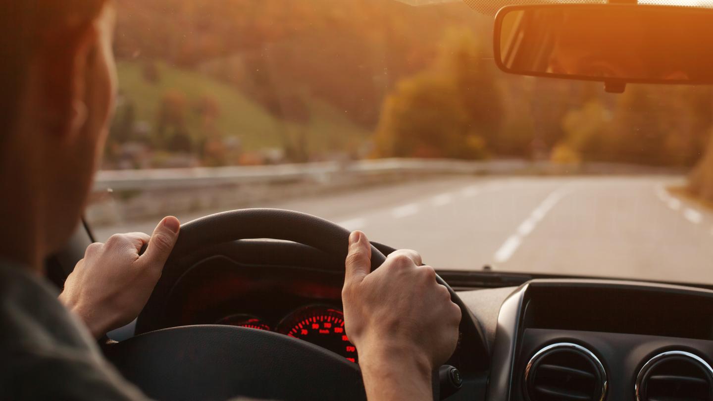 man behind the wheel of a car on the open road