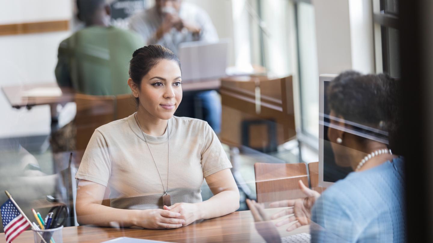 female soldier customer with dog tags sitting behind desk for appointment