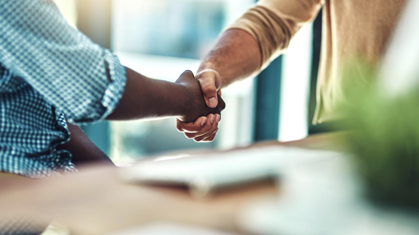 multiracial handshake between two men inside