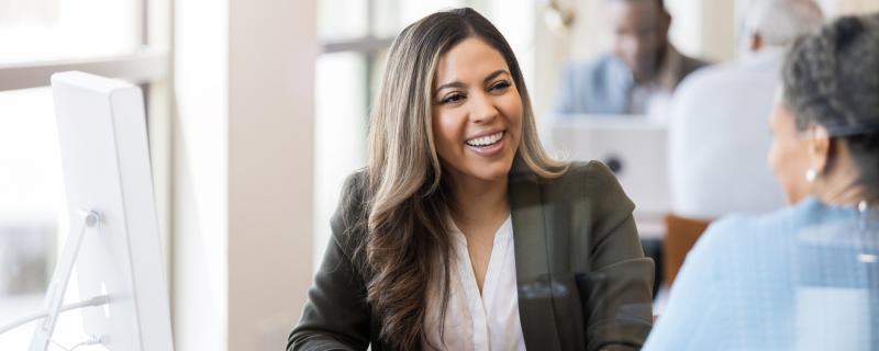 woman smiling at customer behind desk with computer