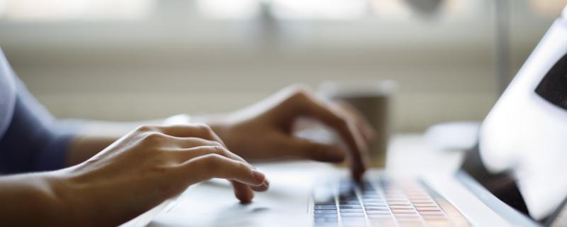 woman's hands using a laptop inside